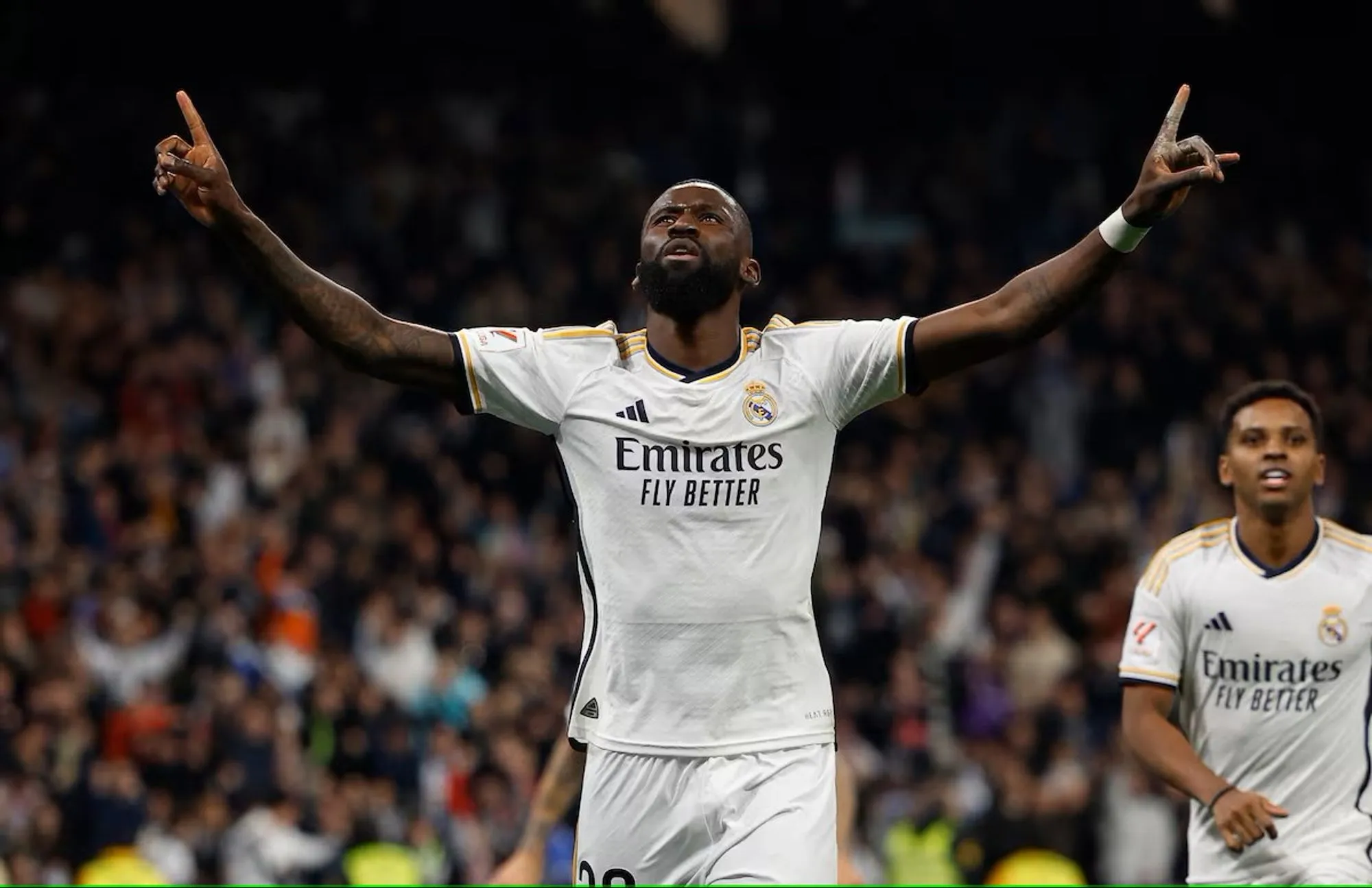 Real Madrid defender Antonio Rüdiger celebrates with arms raised after scoring a goal.